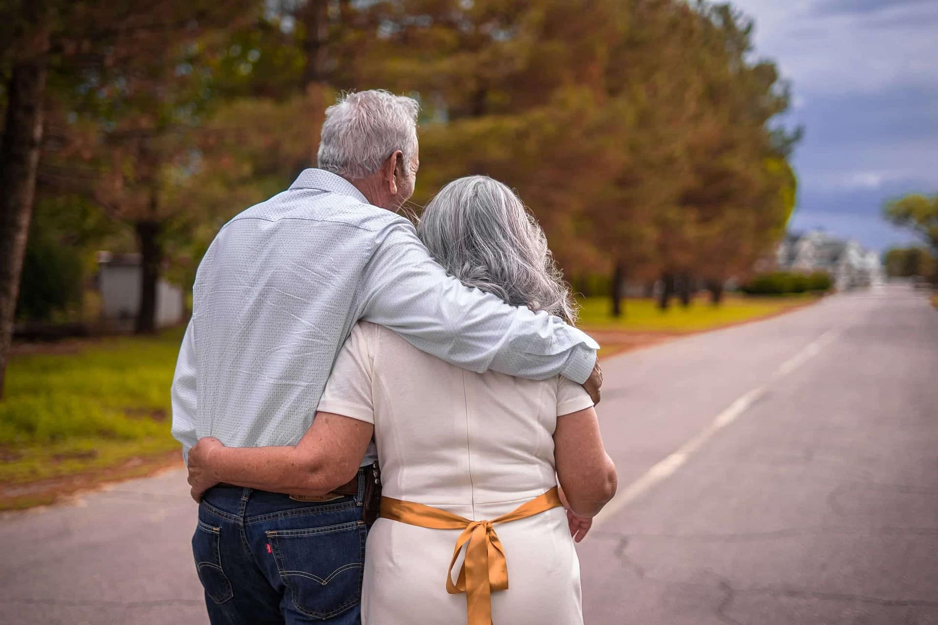 How Does Assisted Living for Couples Work? 3 An older couple walking arm in arm along a road