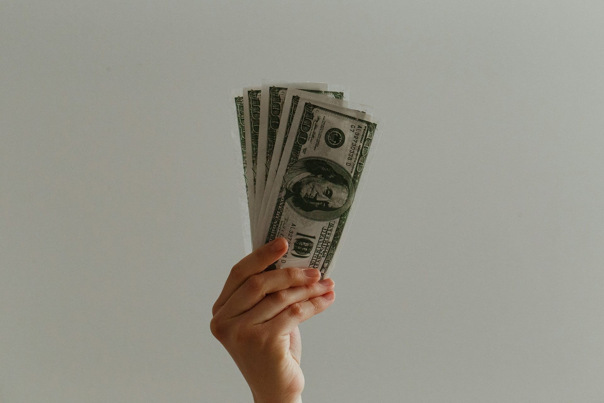 Bereavement Pay: How It Works & How to Qualify 3 A hand holding a fan of banknotes