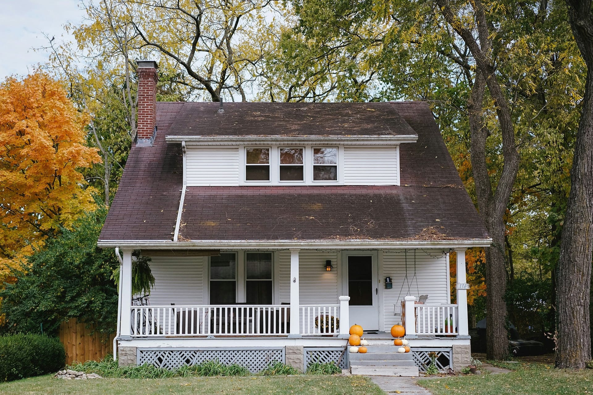 Should I Use an LLC or Living Trust for My Rental Property? 3 A white timber house with a covered porch, surrounded by autumn trees