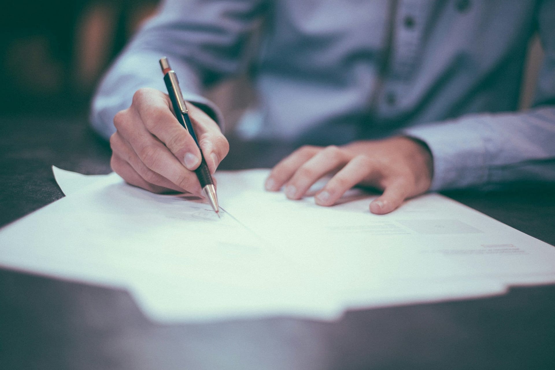 Filing Tax Returns for the Deceased and Their Estate 3 A person writing on a sheet of paper at a desk